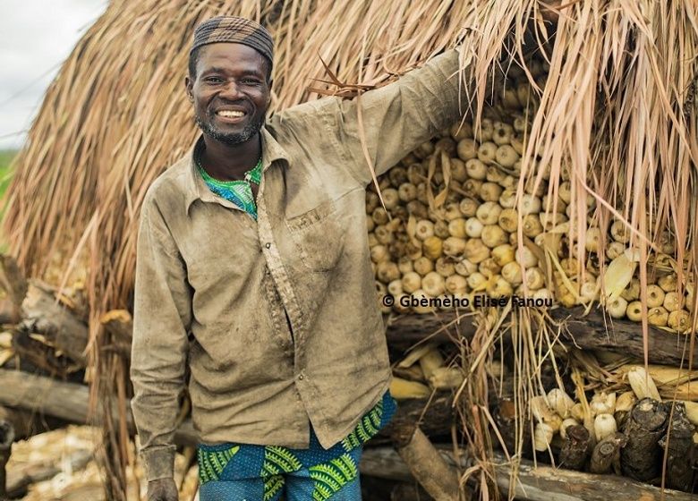 Claver, producteur de coton bio, fi-rement devant son grenier de maïs